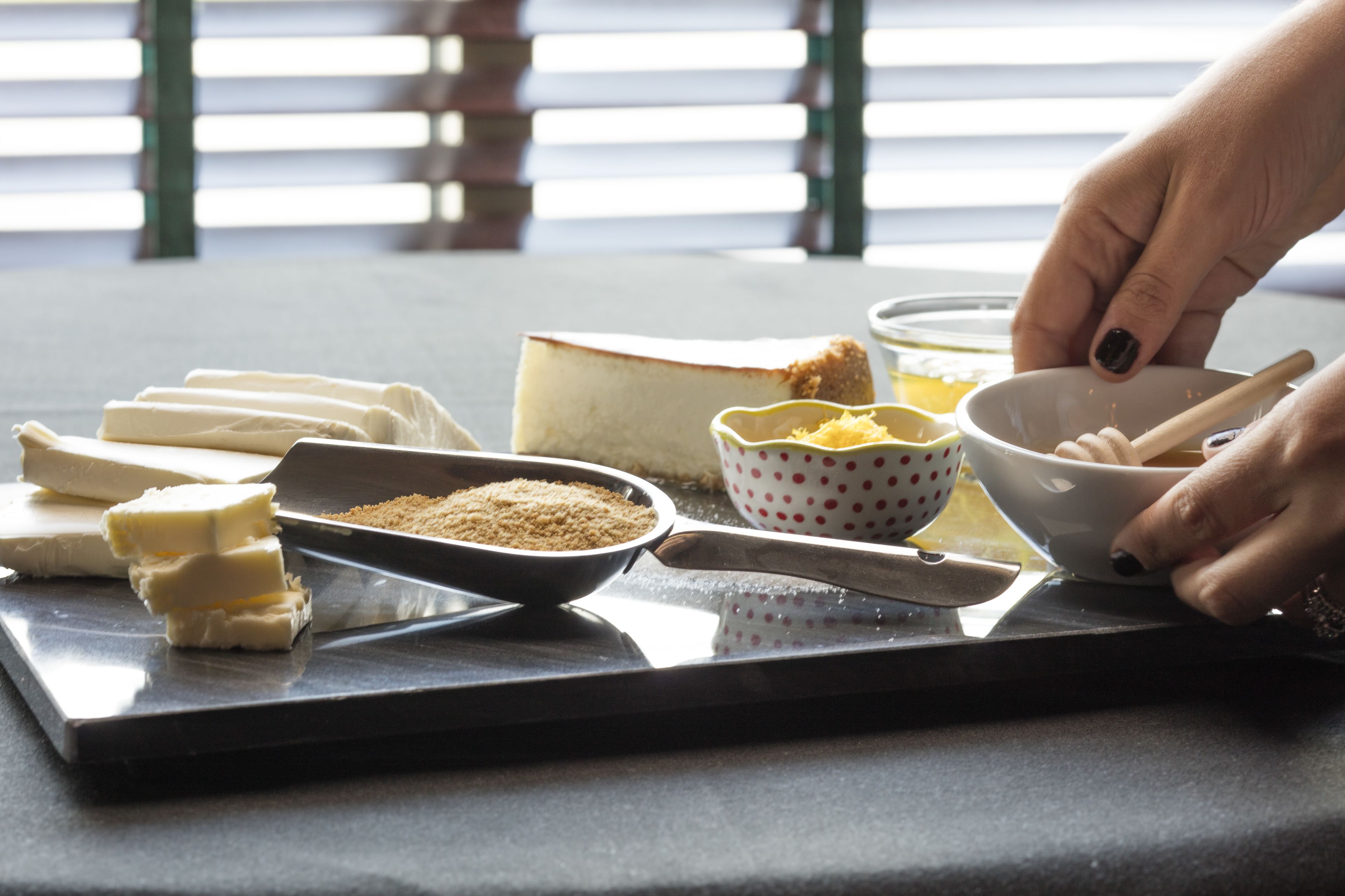 A kitchen counter with various food items and utensils, including a cutting board, a bowl of grated cheese, and a knife.