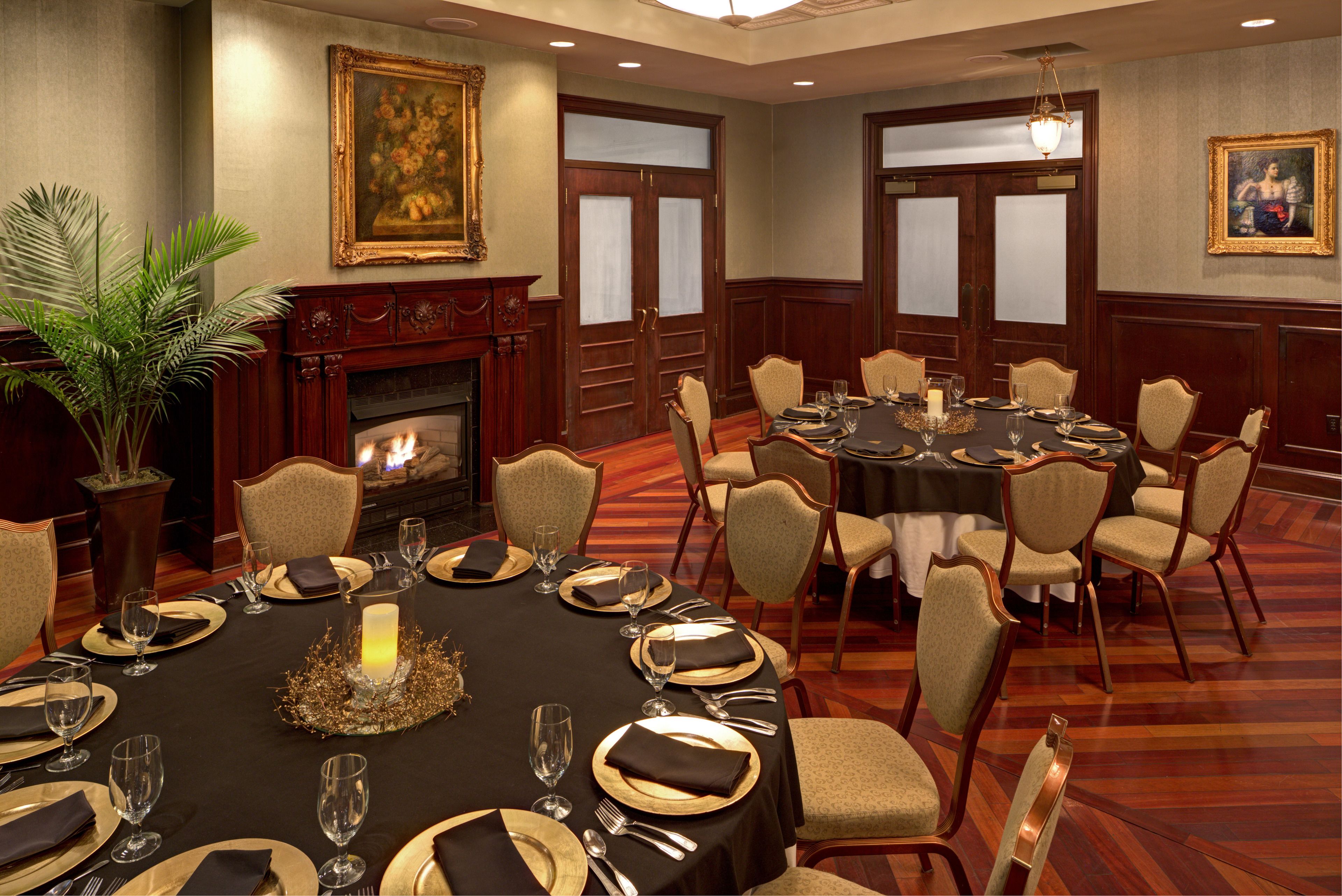 A formal dining room with a fireplace, a round table set for a meal, and several chairs.