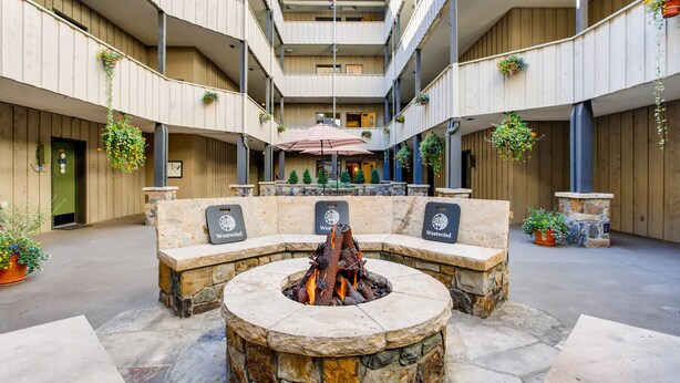 A courtyard with a stone fire pit, seating area, and hanging planters. - Westwind at Vail (Vail)