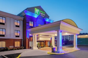 Ein Holiday Inn Express & Suites Gebäude mit überdachter Einfahrt und Backsteinfassade.