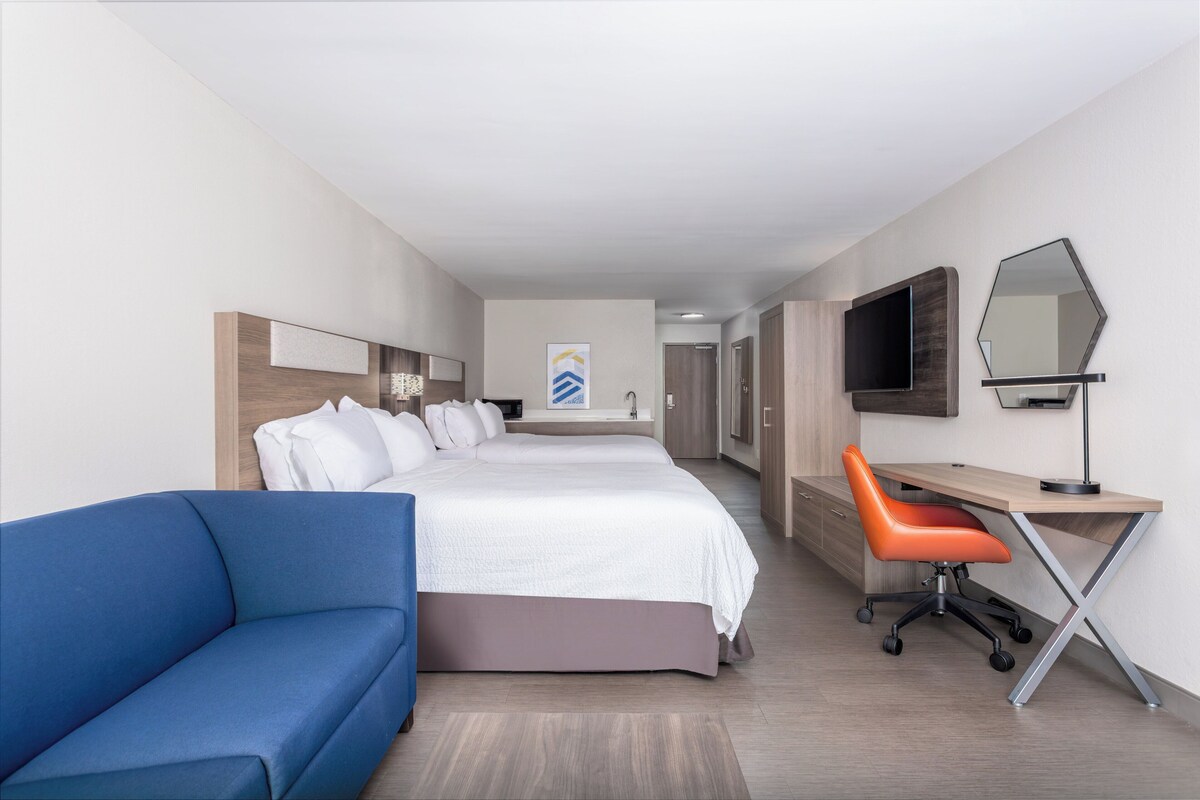 Een hotelkamer met een groot bed, een bureau, een stoel, een televisie en een spiegel.