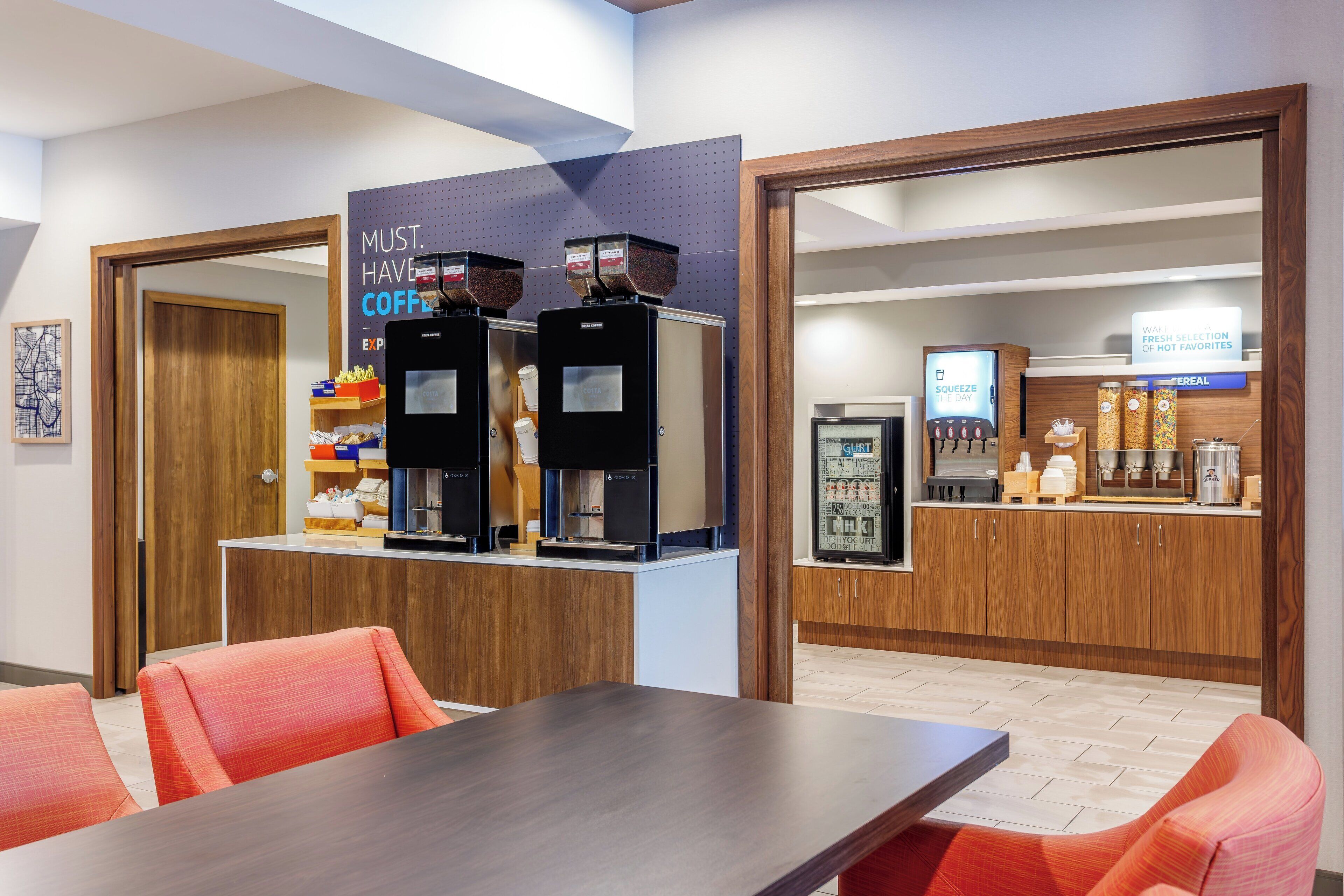 En moderne kaffestation med to espressomaskiner og et kølet display med drikkevarer.