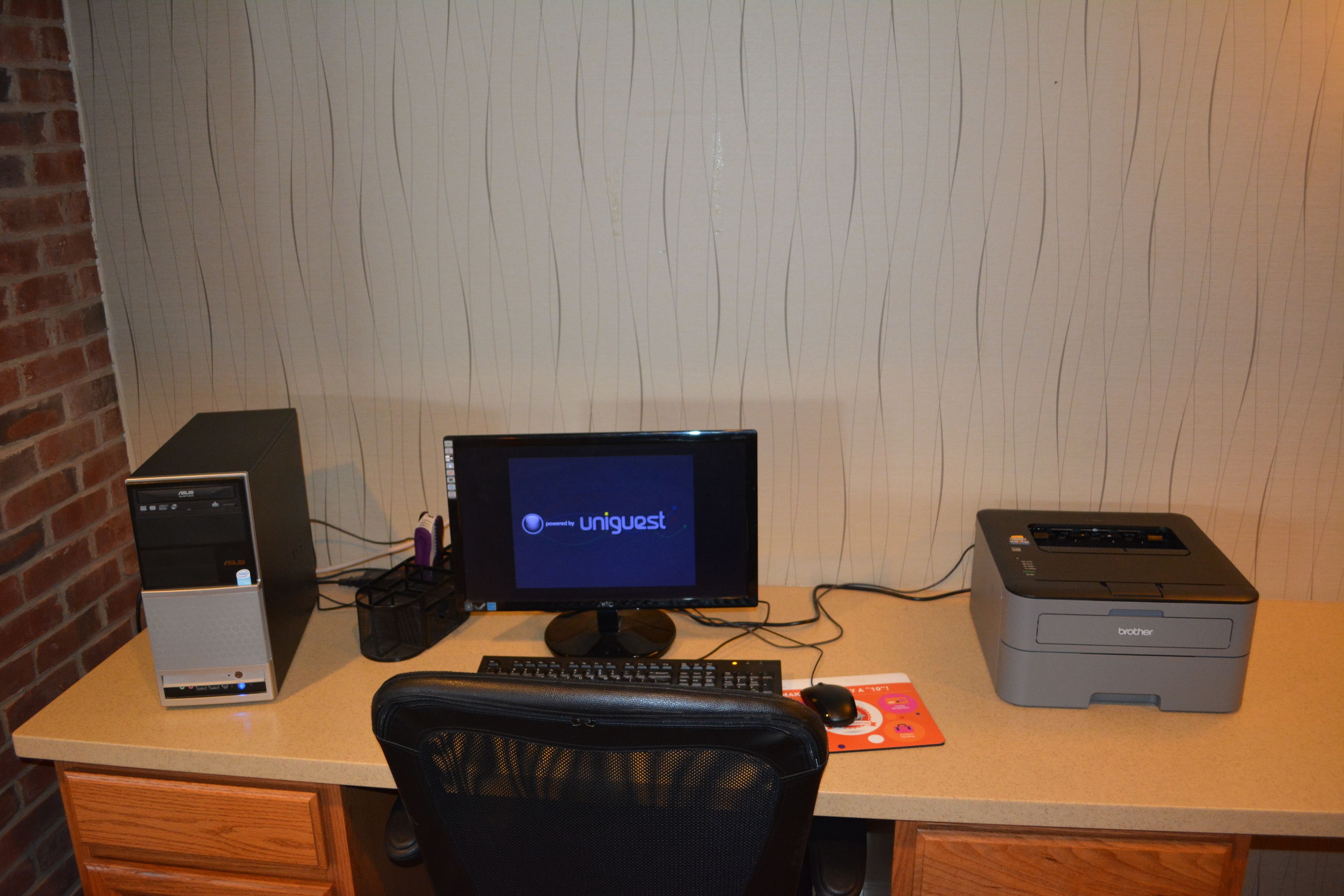 A desk with a desktop computer, monitor, keyboard, mouse, and printer.