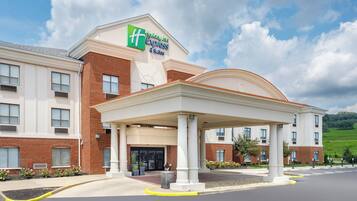 Un bâtiment de l’hôtel Holiday Inn Express & Suites doté d’une entrée abritée, d’une façade en briques et d’un espace paysager agrémenté de plantes en pot.