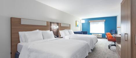 Une chambre d’hôtel avec deux lits, un bureau, une chaise orange et une armoire.