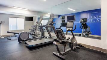 A gym with exercise equipment, a mirror, and a blue wall with text.