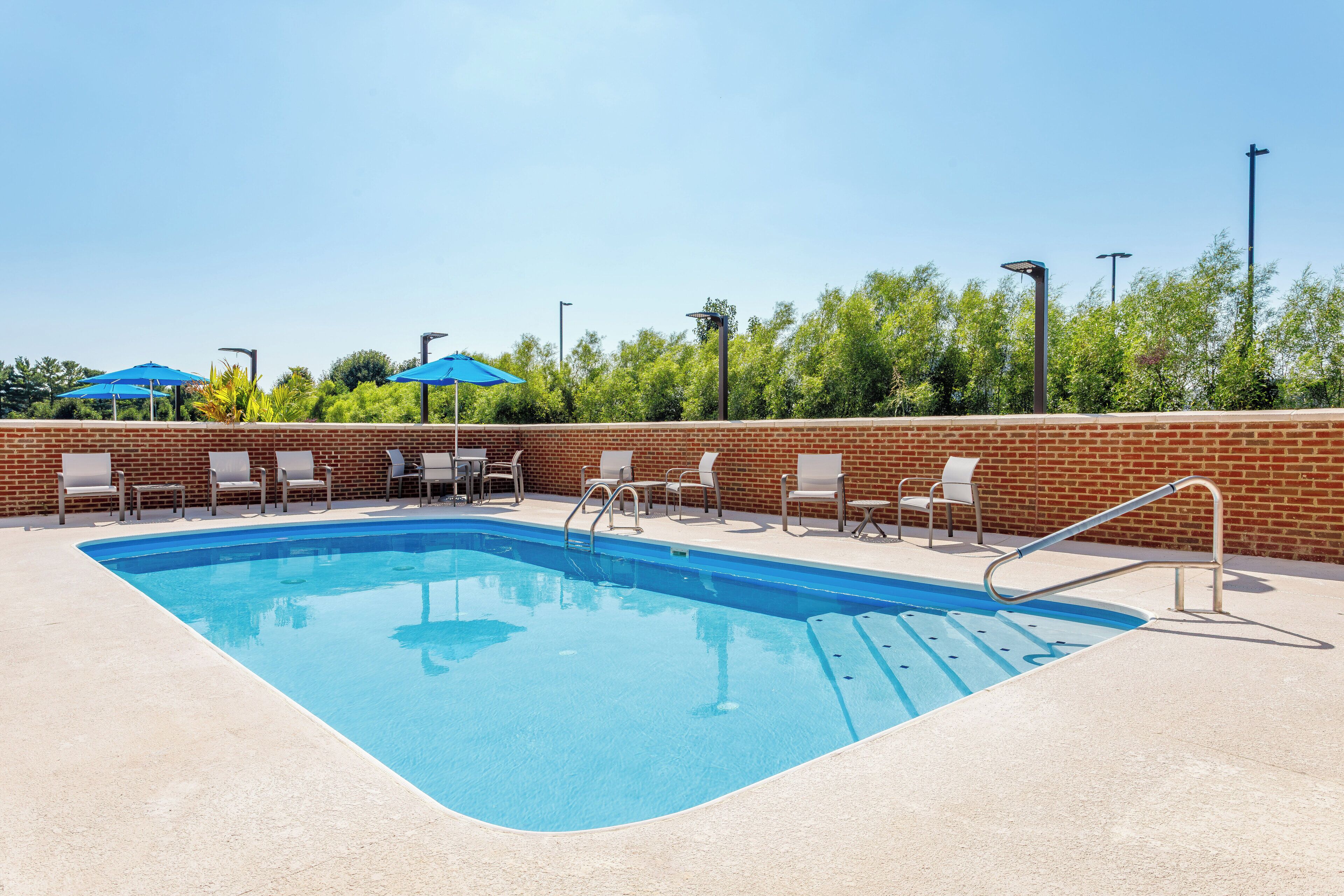 A rectangular swimming pool with a brick wall and a tiled deck.