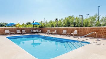 A rectangular swimming pool with a brick wall and a tiled deck.