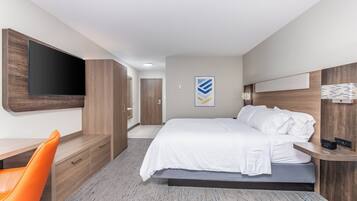 Una habitación de hotel moderna con una cama, un escritorio, una silla y un televisor montado en la pared.