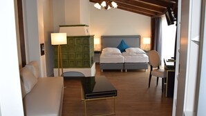 Habitación de hotel con cama, dos mesitas de noche, un escritorio, una silla, un armario verde y una araña.