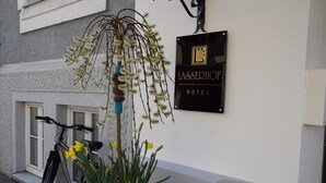 Señal del Hotel Lassserhof, con una bicicleta estacionada afuera y una maceta con flores amarillas en primer plano.