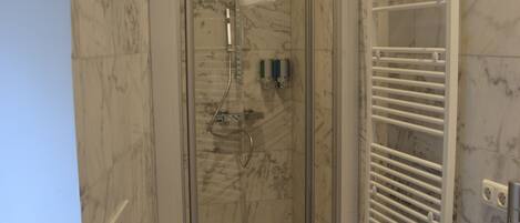 A modern bathroom with a glass-enclosed shower, a white toilet, and a white sink.