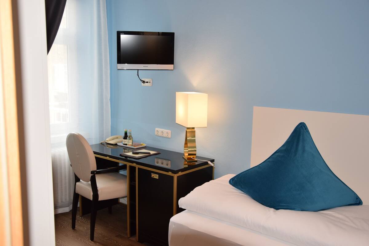 Une chambre d’hôtel avec un lit, un bureau doté d’une lampe, une télévision et une chaise.
