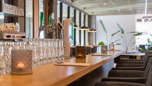 Una zona de bar con una barra larga, varios vasos y algunas sillas.