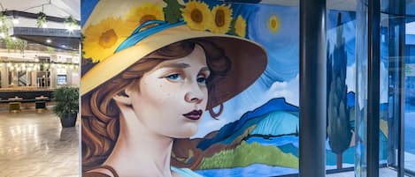 A mural with a woman wearing a hat and a landscape with sunflowers.
