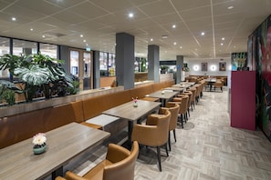 A modern restaurant with long wooden tables and cushioned booths, a tiled floor, and large windows offering views of the outside. - Best Western Amsterdam (Amsterdam)