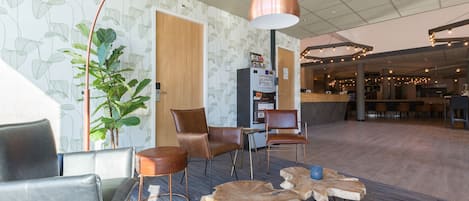 Un vestíbulo moderno con sillones de cuero, una máquina de café y una planta grande.