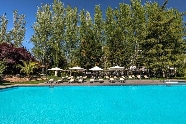 Una piscina al aire libre de temporada, sombrillas