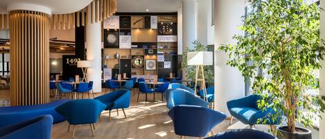A modern interior with blue chairs, wooden accents, and a large potted plant.