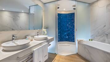 Un baño moderno con dos lavamanos, un espejo grande, una ducha con pared azul geométrica y una bañera.