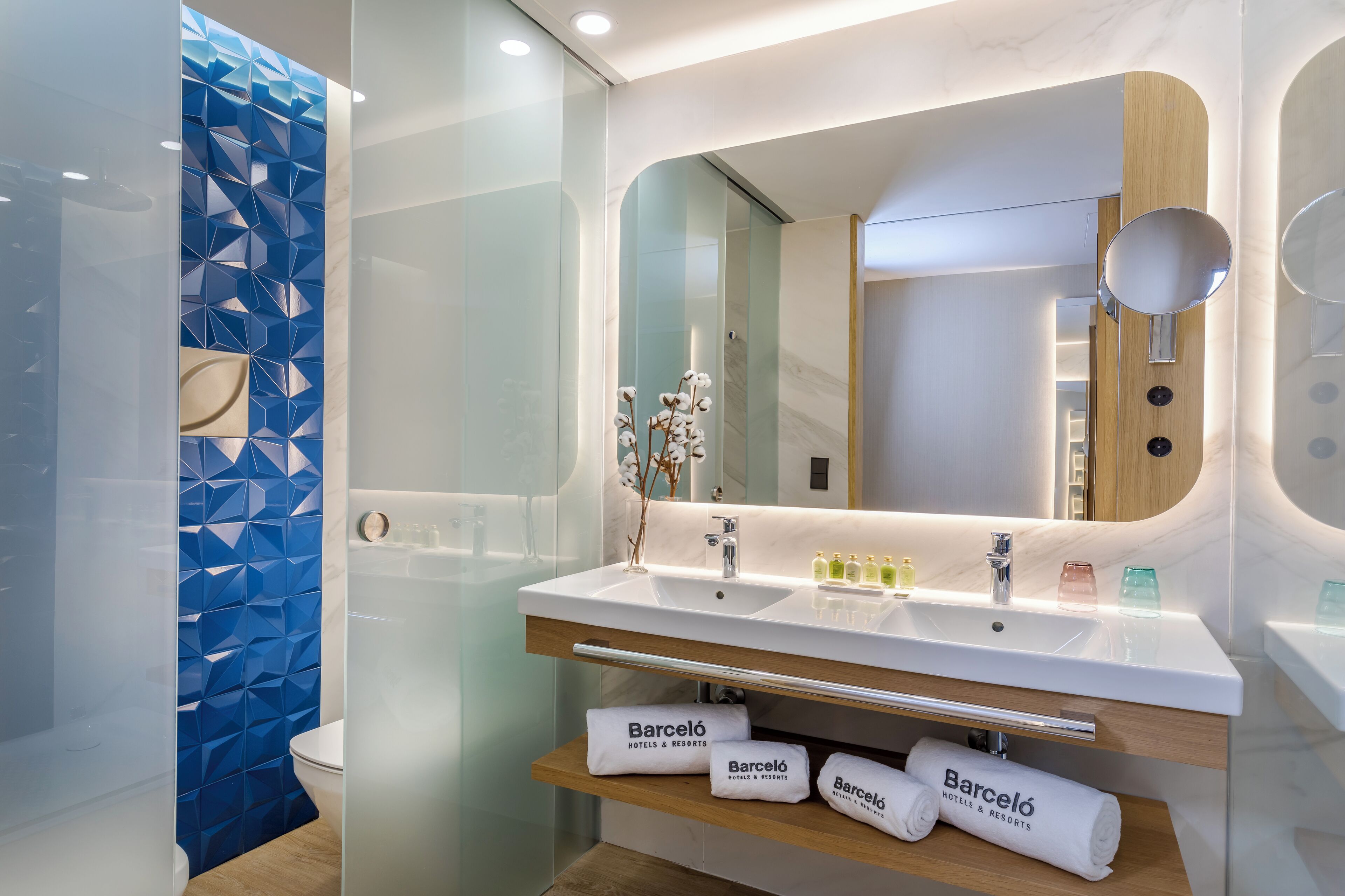 Un baño moderno con lavamanos doble, un espejo grande y una cabina de ducha de vidrio.