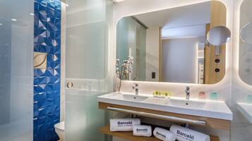 Un baño moderno con lavamanos doble, un espejo grande y una cabina de ducha de vidrio.
