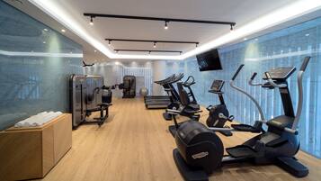 Un gimnasio moderno con diverso equipo de ejercicio, suelo de madera y un amplio ventanal con vistas.