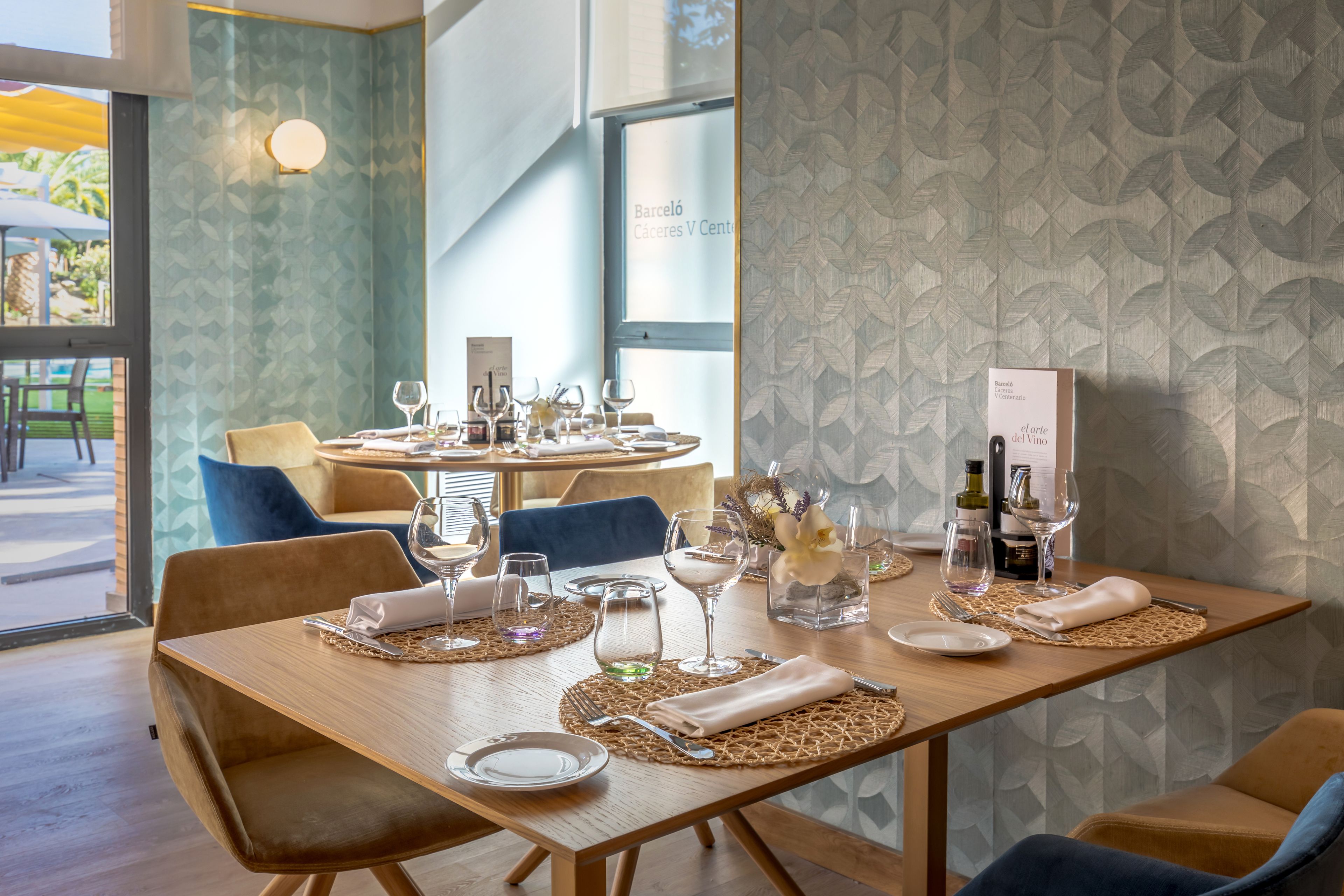 A dining area with a wooden table set for a meal, surrounded by blue chairs.