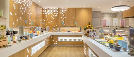 A modern kitchen with wooden accents, a central island with a sink, and various food items displayed on the counter.