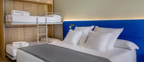 A hotel room with a large bed, a lower bunk bed, and a wardrobe with labeled compartments.