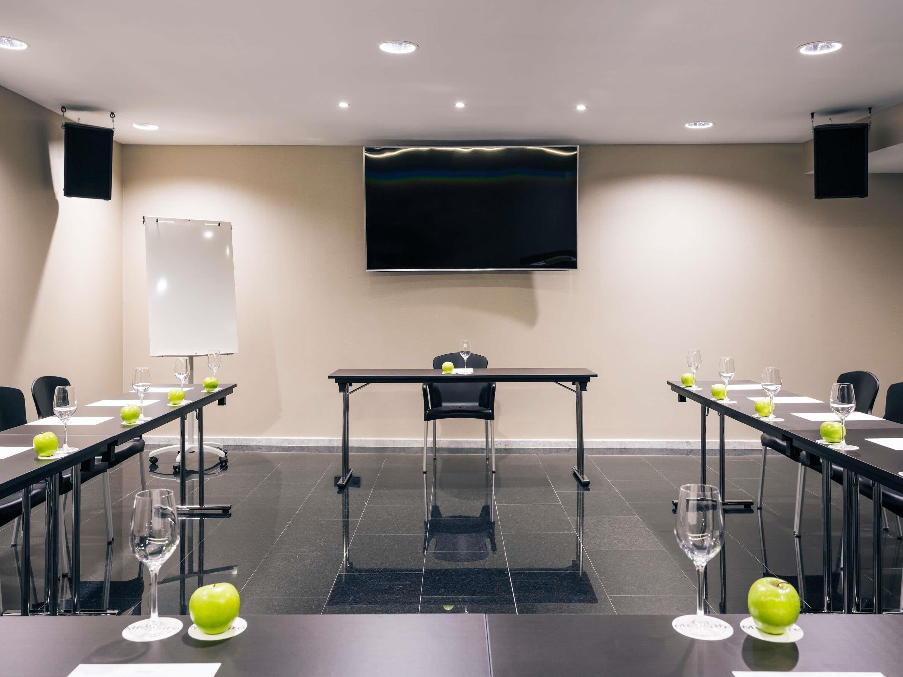 A conference room with a long table, chairs, a projector screen, and a whiteboard.