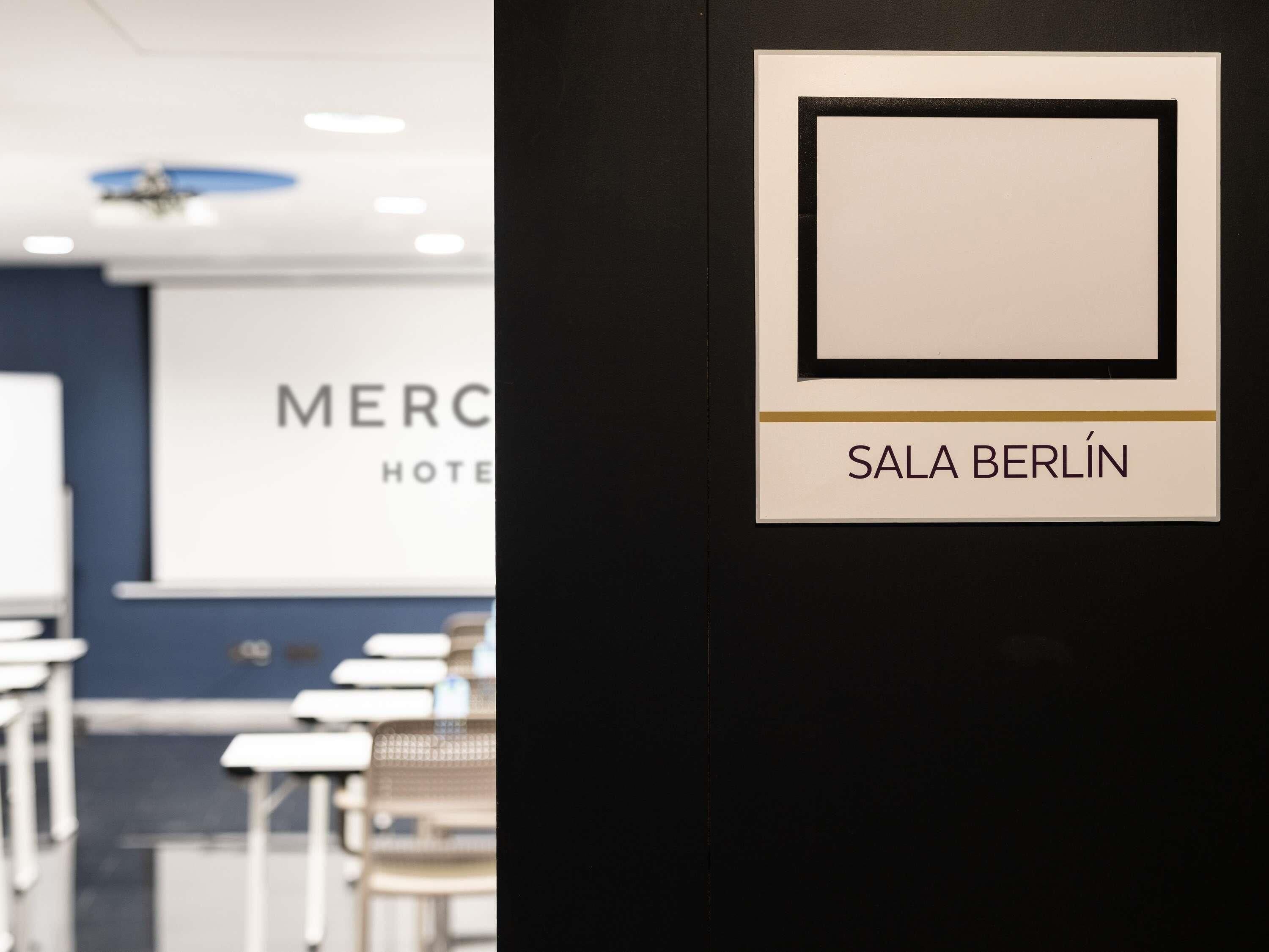 A hotel interior with a sign for 'SALA BERLIN' and a blurred background with a 'MERC HOTEL' sign.