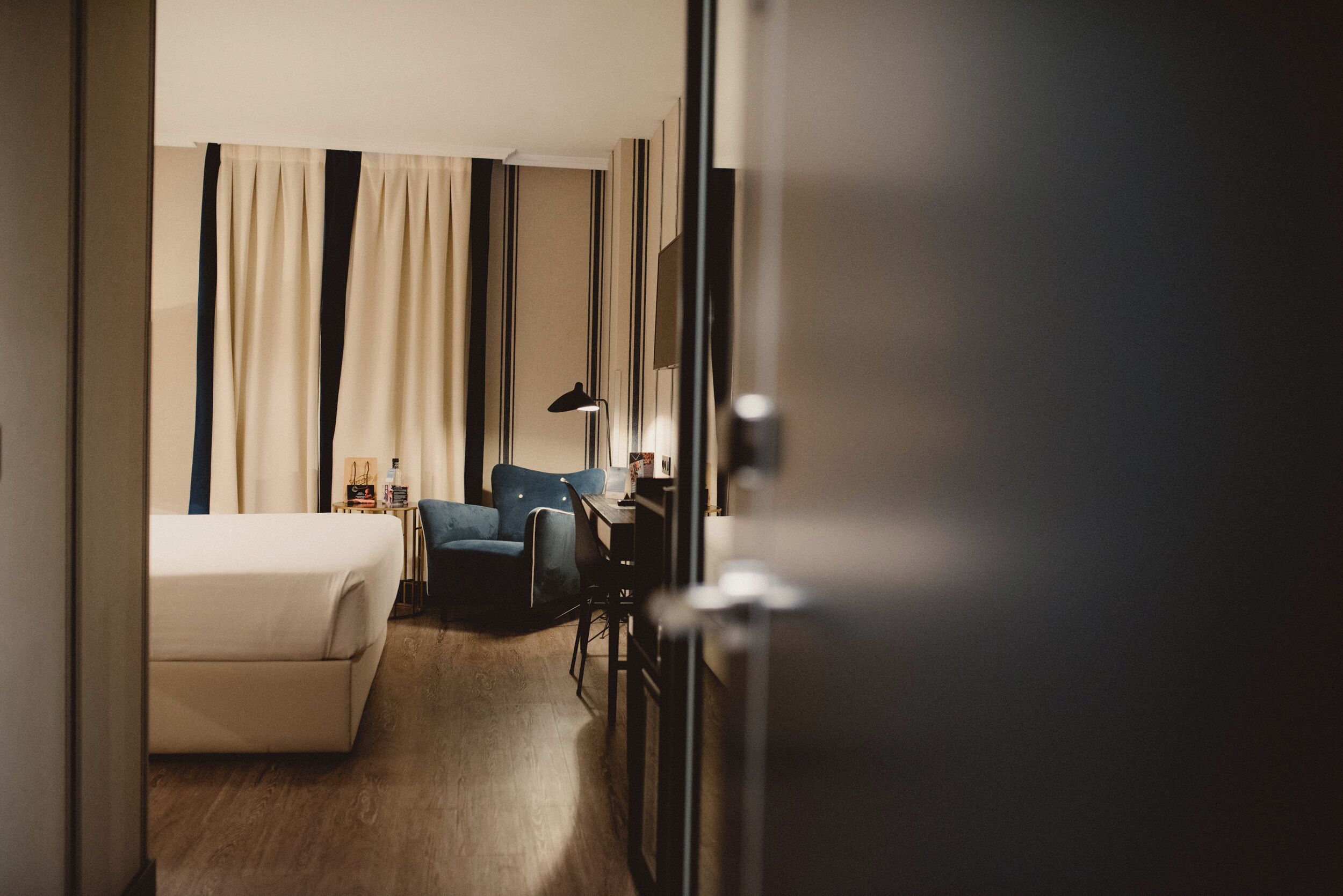 Una habitación de hotel con una cama, un escritorio, una silla y una lámpara.