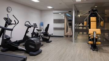 Et fitnesscenter med løbebånd, crosstrainere og styrkemaskine.