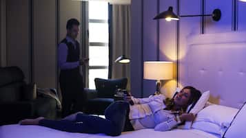 A hotel room with a bed, a standing lamp, and a chair.