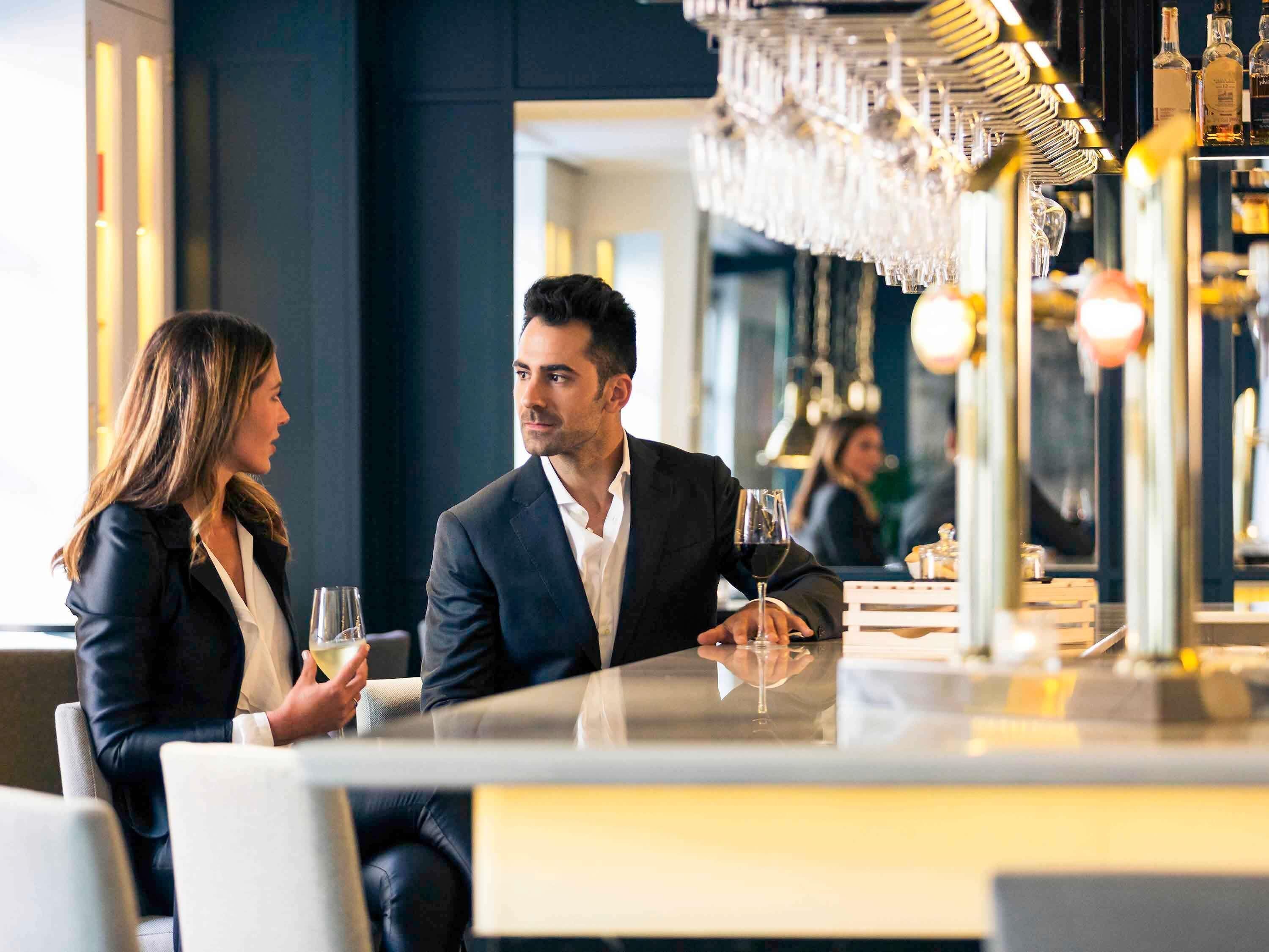 A couple seated at a table in a modern restaurant with a bar area in the background.