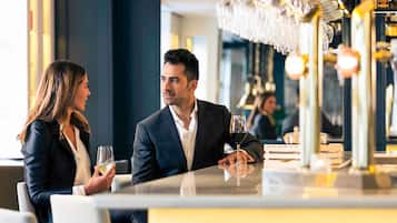 A couple seated at a table in a modern restaurant with a bar area in the background.
