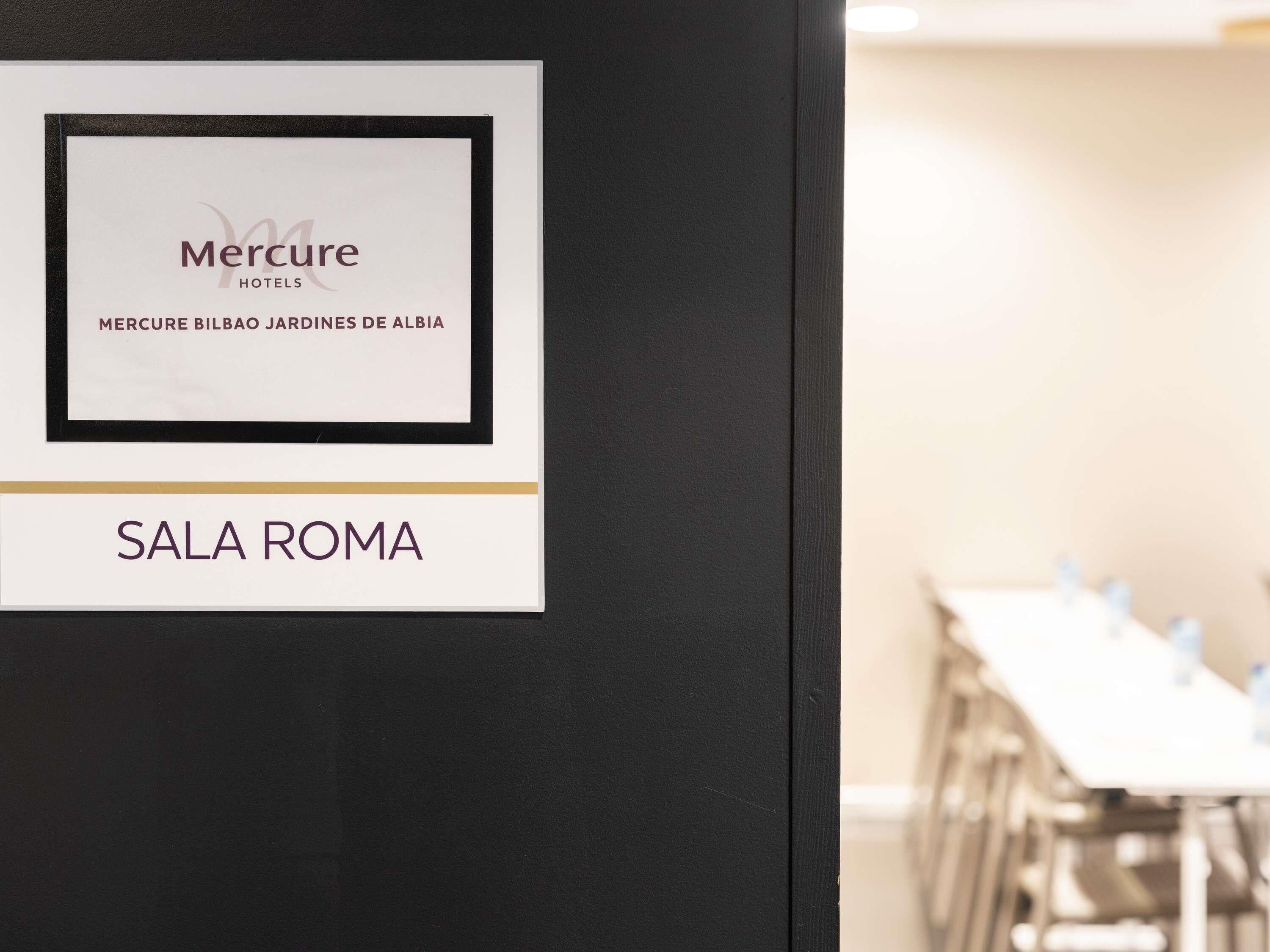 A framed sign with 'Mercure Hotels' and 'Mercure Bilbao Jardines de Alba' text, and a sign below reading 'Sala Roma'.