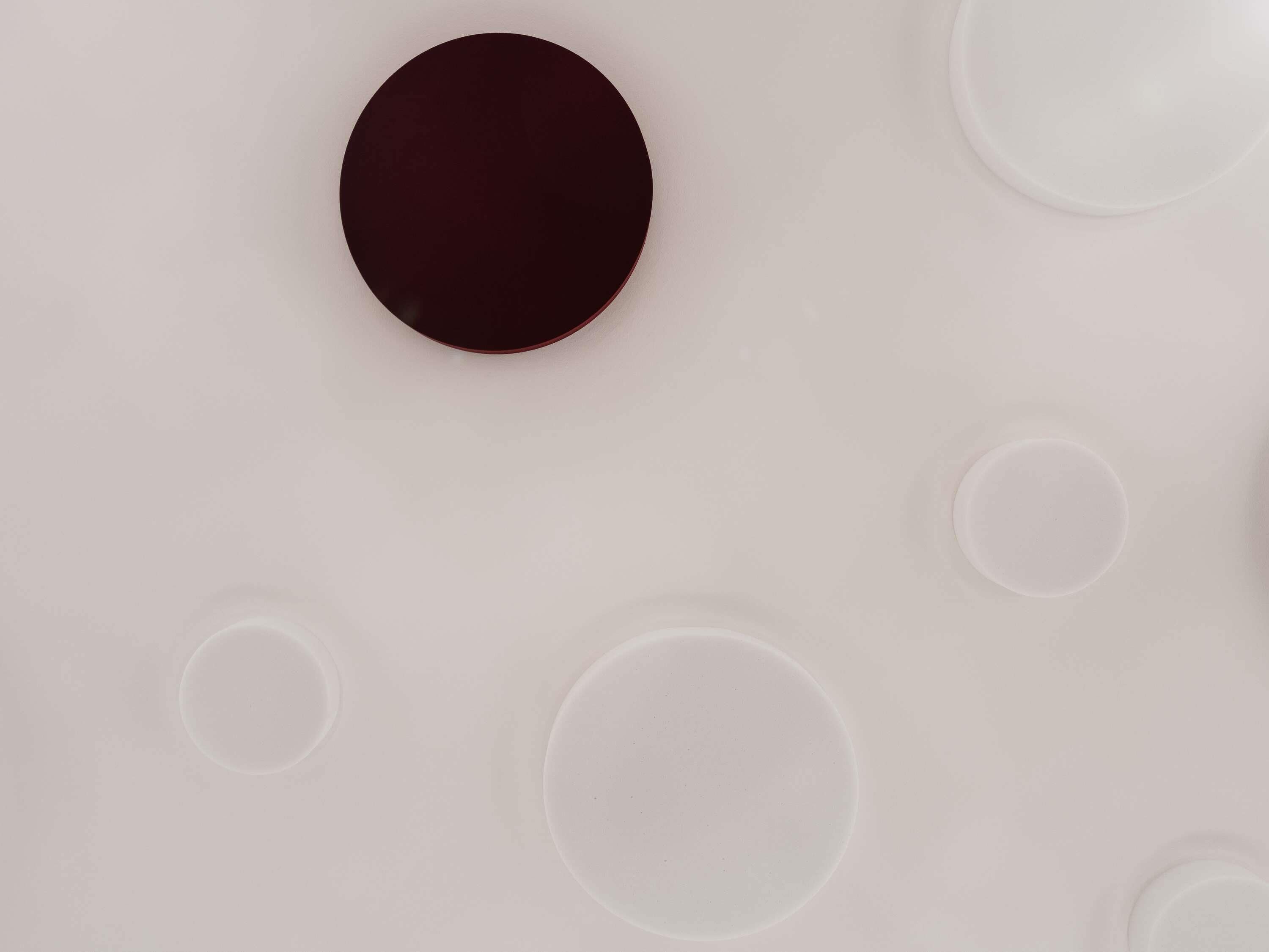Un plafond orné de motifs circulaires, comprenant un grand cercle foncé et plusieurs petits cercles clairs.