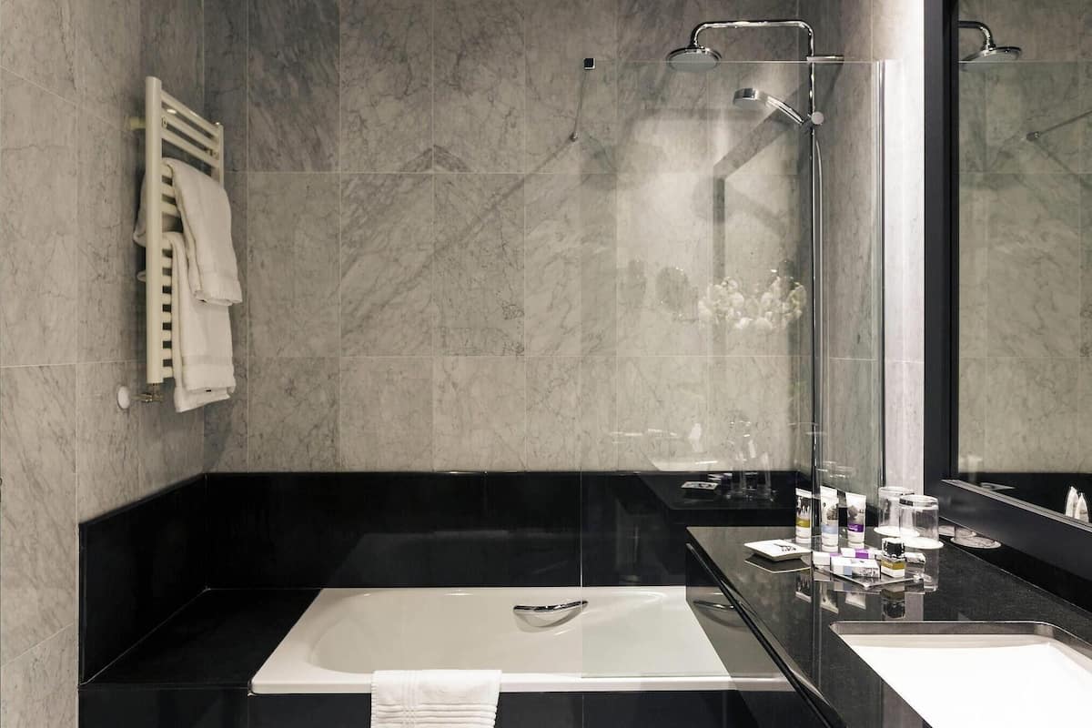 A modern bathroom with a large bathtub, a glass shower enclosure, and a large mirror.