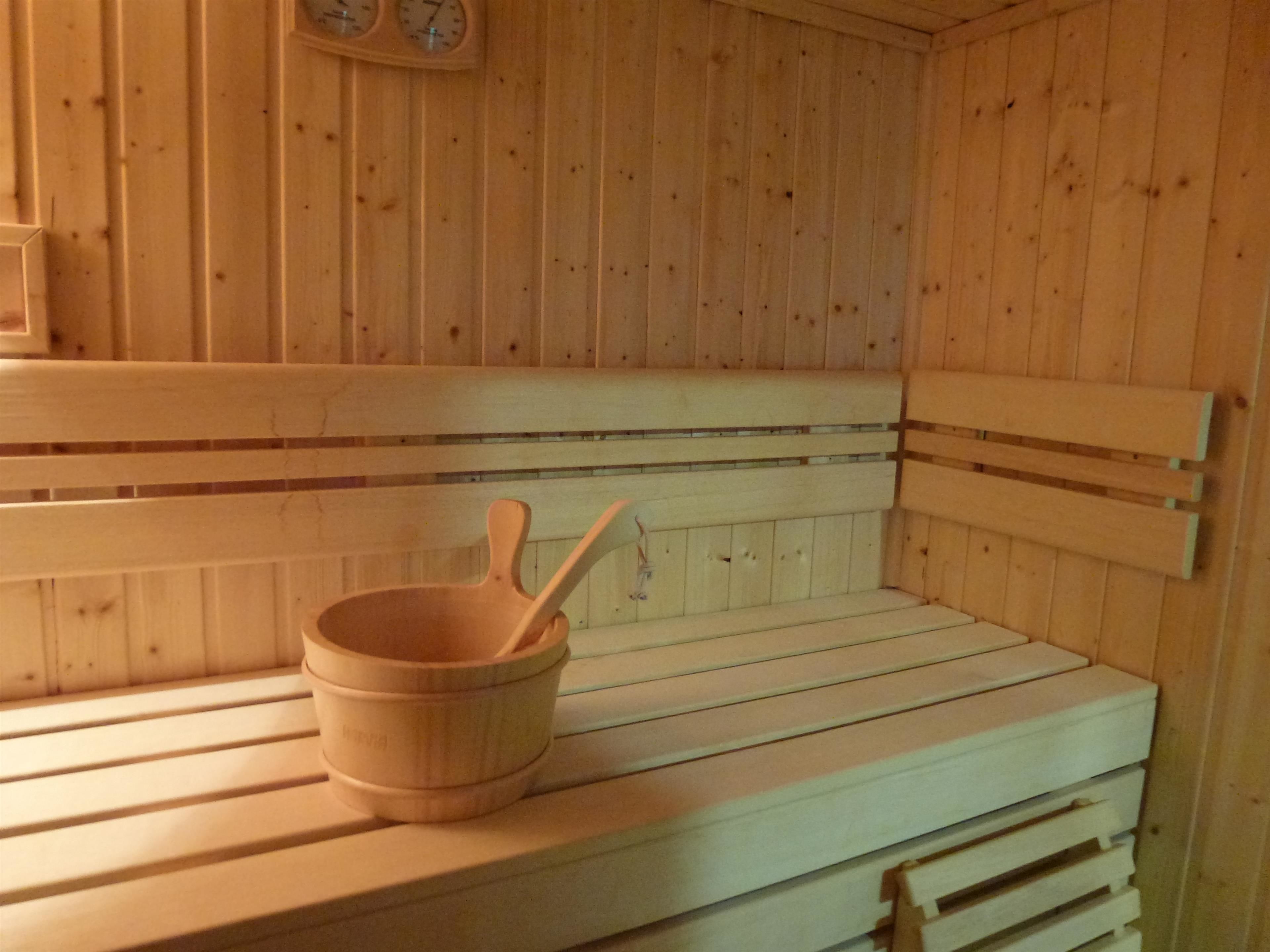 A wooden sauna bench with a wooden bucket and spoon.