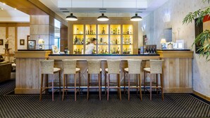 Un espace bar avec un barman, un comptoir en bois et des tabourets de bar.