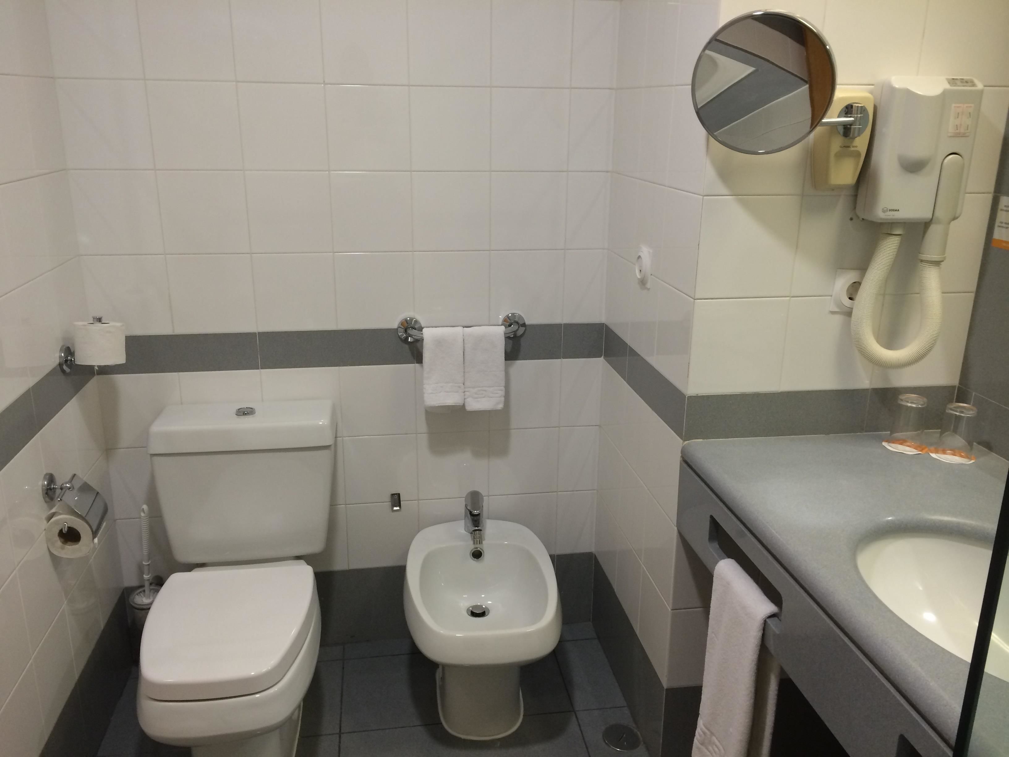 A bathroom with a toilet, bidet, and sink.