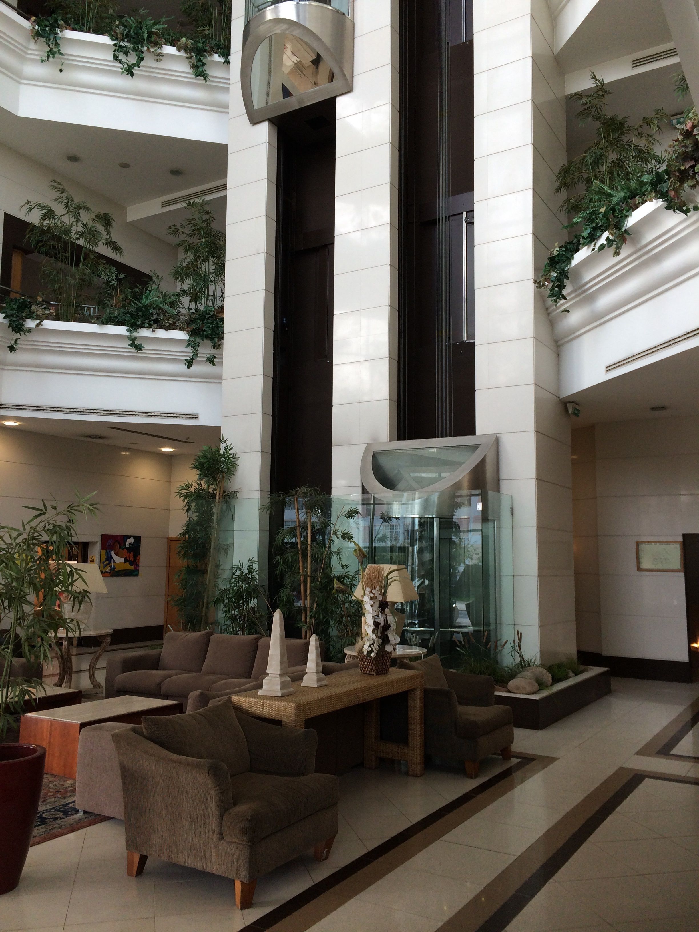 Un hall d’entrée spacieux avec de hauts plafonds, de nombreux espaces de détente et une abondance de plantes d’intérieur.