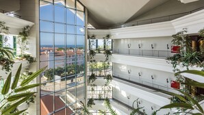 Un atrium à plusieurs niveaux, doté de murs en verre, de plantes d’intérieur et offrant une vue sur la mer.