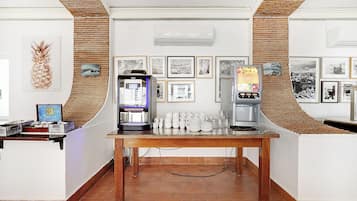 A coffee station with a coffee machine, a beverage dispenser, and a table with cups and plates.