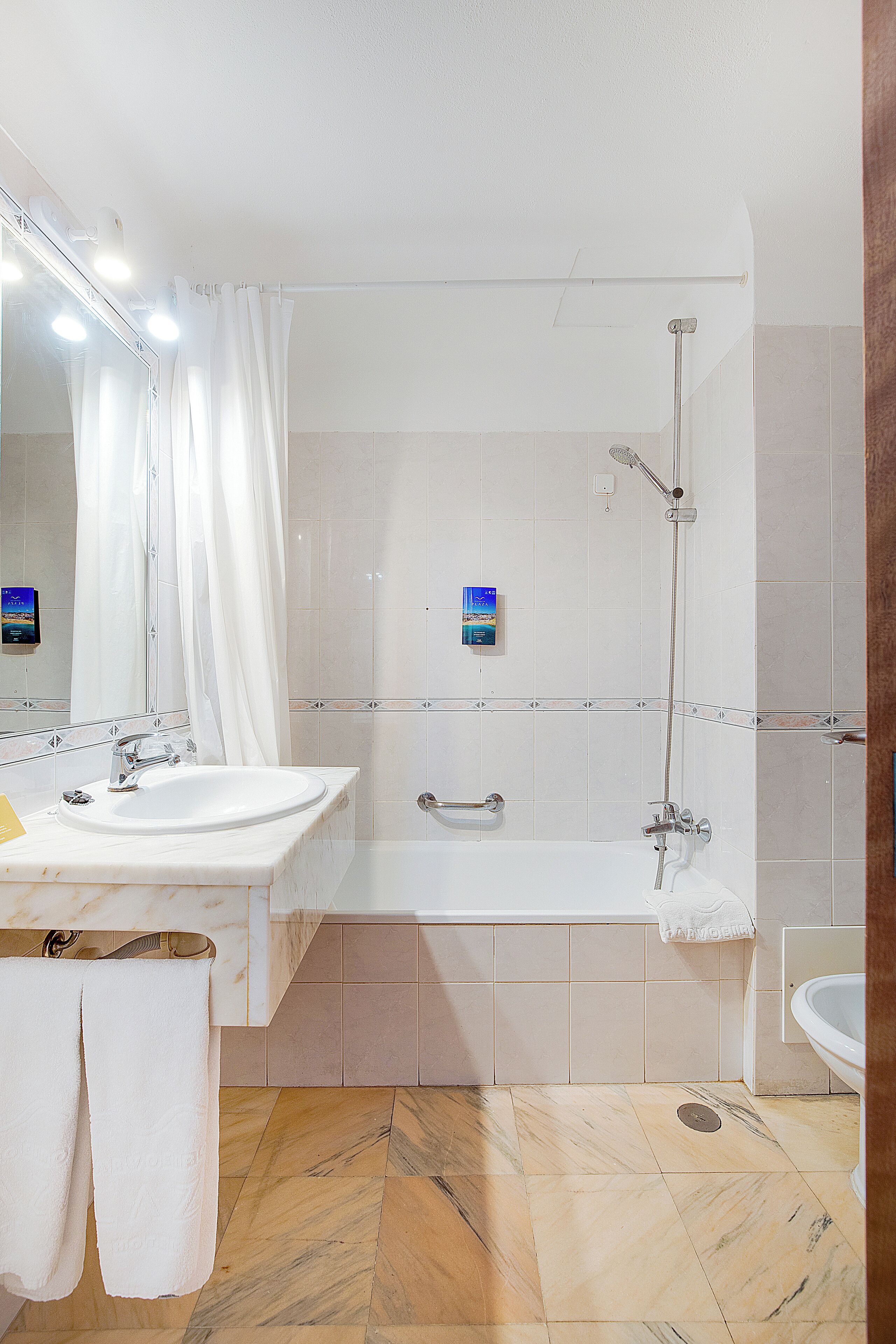 Een badkamer met een wastafel, spiegel, douche en toilet.