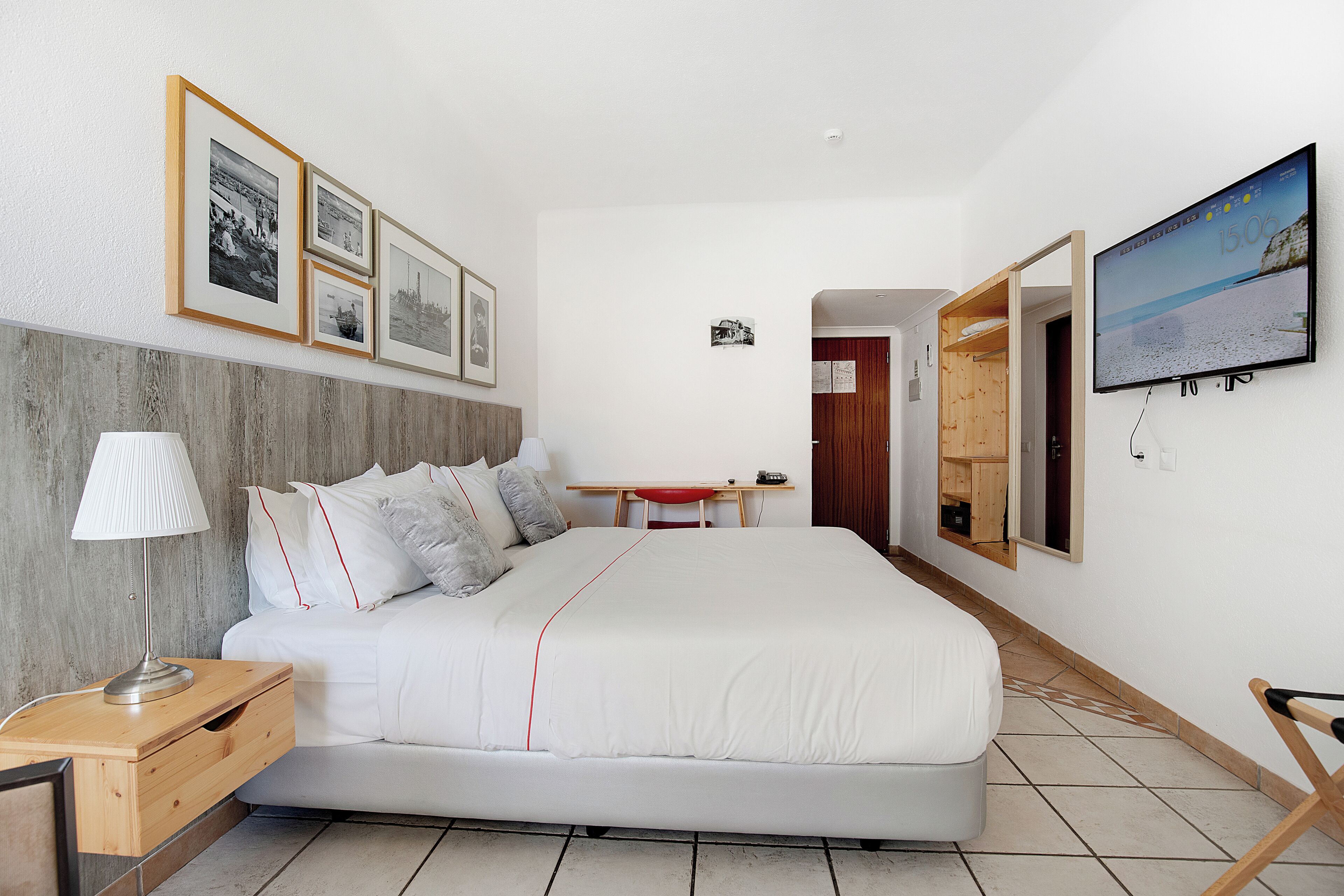 Une chambre moderne avec un grand lit, un bureau, une télévision et des tableaux encadrés accrochés au mur.