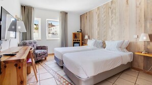 Hotelkamer met twee bedden, een bureau, een stoel, een televisie en uitzicht.