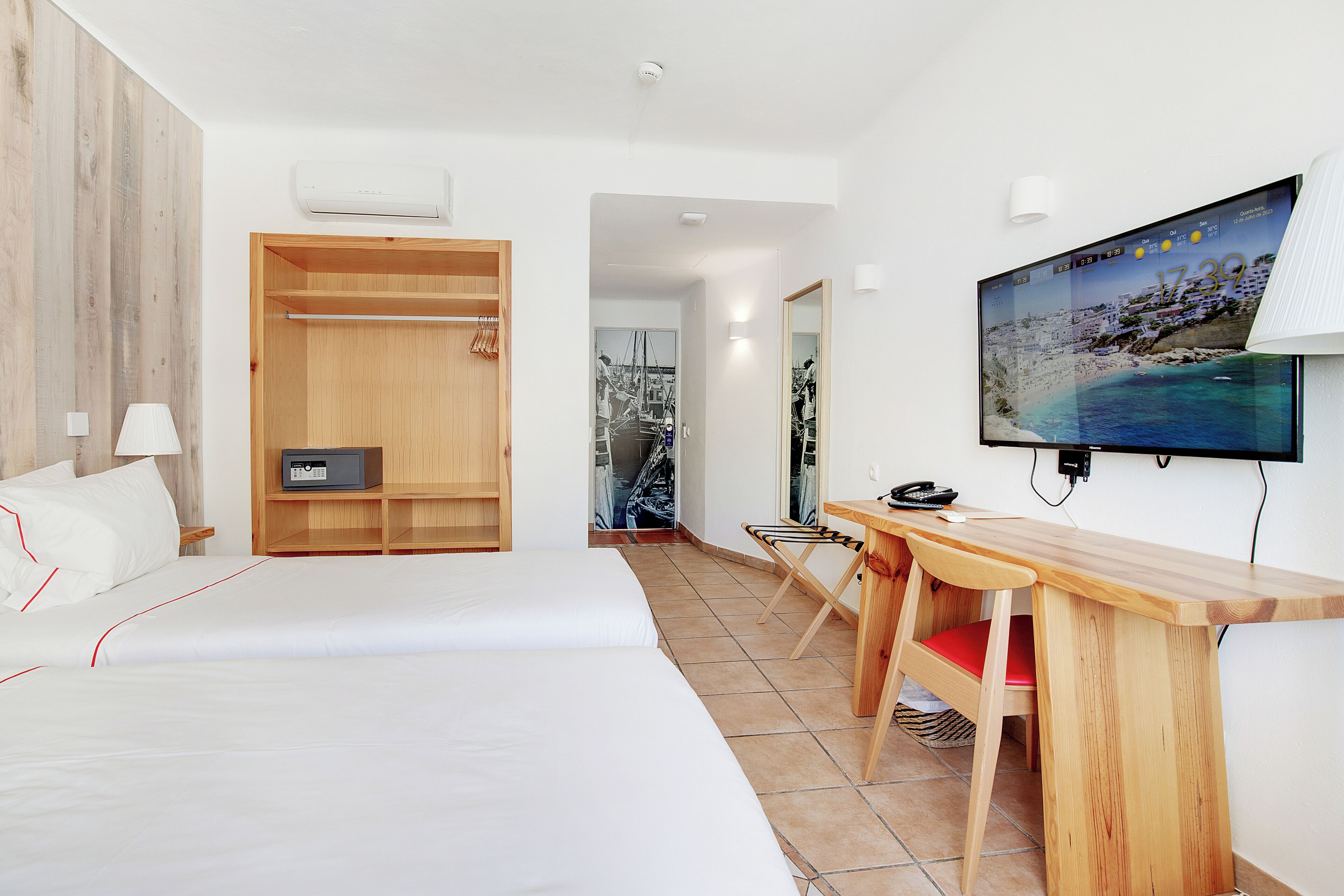 Ein Hotelzimmer mit einem Bett, einem Holztisch, einem Stuhl, einem Fernseher und einem Kleiderschrank.